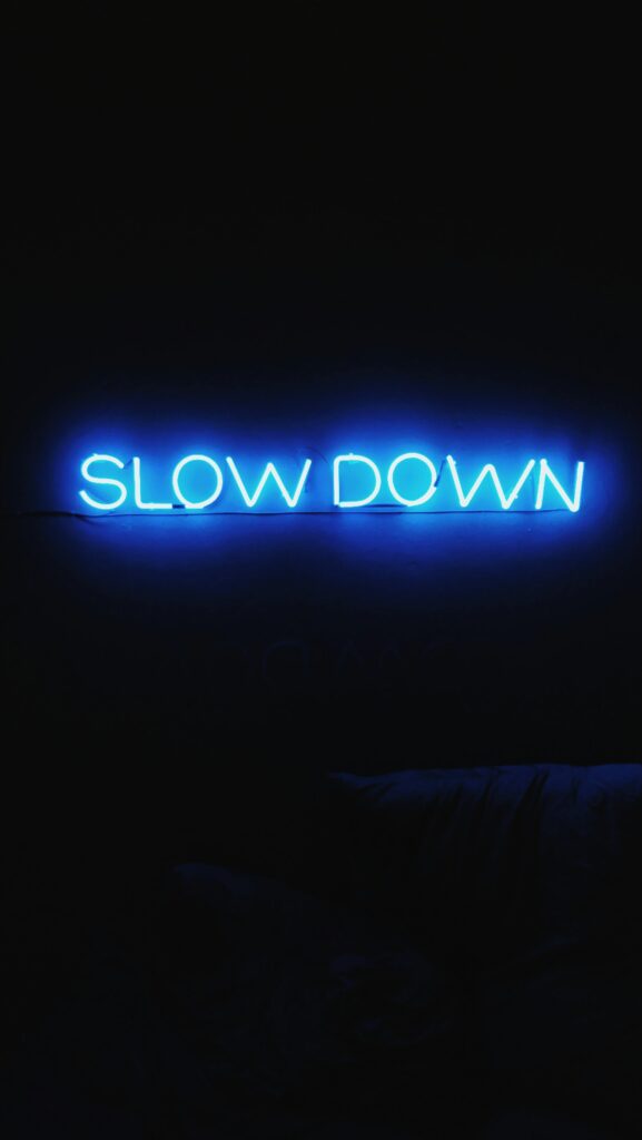 A glowing blue neon sign reads 'Slow Down' against a dark backdrop, creating a modern aesthetic.