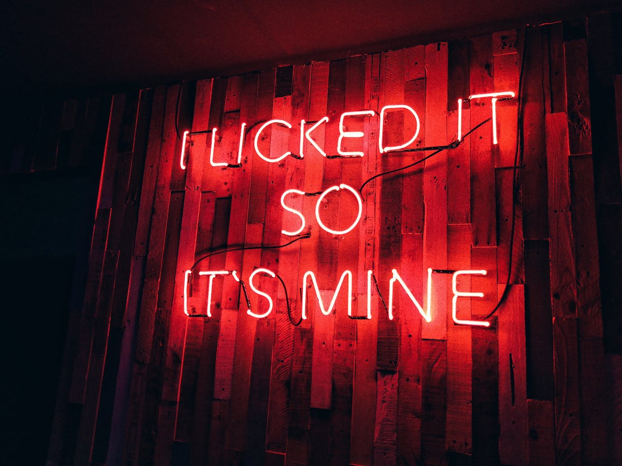 contact-img Vibrant red neon sign displays playful text on a rustic wooden wall, perfect for modern decor themes.